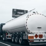 Caminhão-tanque visto por trás trafegando por uma rodovia, transportando combustível.