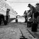 Grupo de trabalhadores limpa uma passagem de concreto em espaço público.