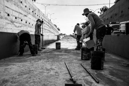 Grupo de trabalhadores limpa uma passagem de concreto em espaço público.
